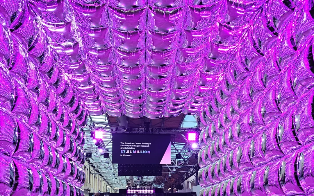 A silver balloon arch with purple light shining through.